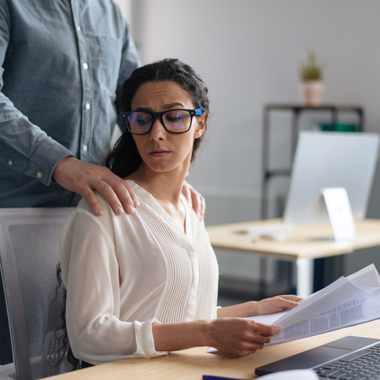 male employee touching disgusted woman in an office