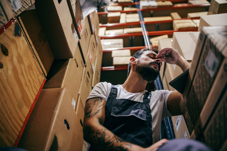 Tattooed bearded worker in overalls having hard day on the work.