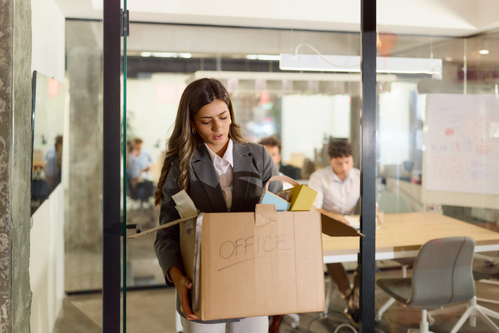 employee carrying box of possessions out of the office
